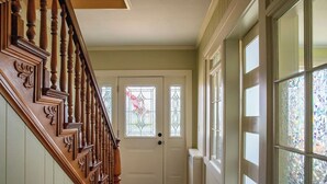 A hallway with a wooden staircase, a white door with stained glass windows, and a radiator. - Riverview, 5BR, Hot tub, Fireplace, Arcade Game (Minneiska)