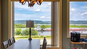 A room with a table and chairs, a lamp, a coffee maker, and a view of a river with boats. - Riverview, 5BR, Hot tub, Fireplace, Arcade Game (Minneiska)