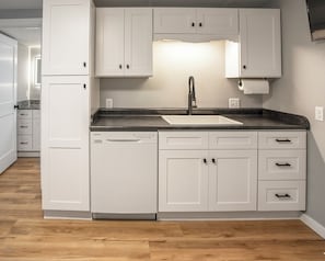 Een moderne keuken met witte kasten, een zwart aanrecht en een roestvrijstalen spoelbak.