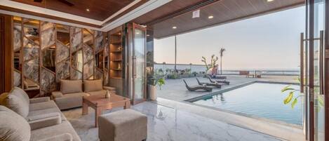 A modern living room with a pool and a view of the ocean.