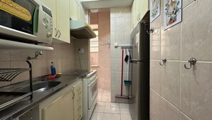 Eine schmale Küche mit einem Herd, Spüle und einem Kühlschrank.