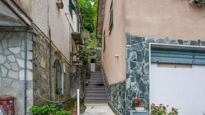 A narrow alleyway with a staircase leading to a building with stone walls and a metal gate. - Amazing home in Ferriere with WiFi (Ferriere)