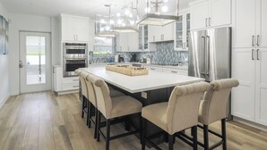 A modern kitchen with a central island, stainless steel appliances, and a unique pendant light. - Cayman Beach Escape - luxury ground floor 2BR (Savannah)