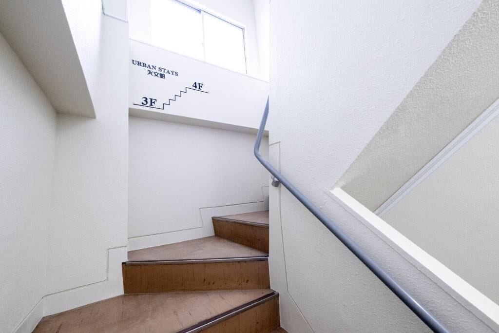 A staircase with a handrail, white walls, and a window.