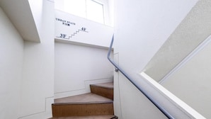 Una escalera con barandilla, paredes blancas y una ventana.