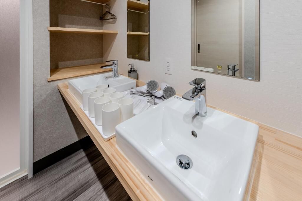 Un baño moderno con un lavamanos grande de color blanco, un espejo y un estante con artículos de aseo.