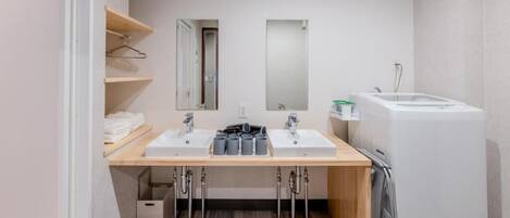 A modern bathroom with two sinks, a mirror, and a built-in washing machine.