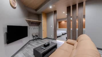 Una habitación de hotel moderna con una televisión de pantalla plana, un sofá, una mesa de centro y una cama con cabecera de madera.