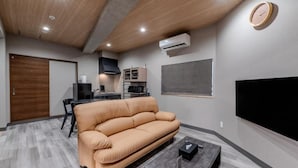 Una sala de estar moderna con un sofá, una mesa de centro, un televisor y un comedor con sillas.
