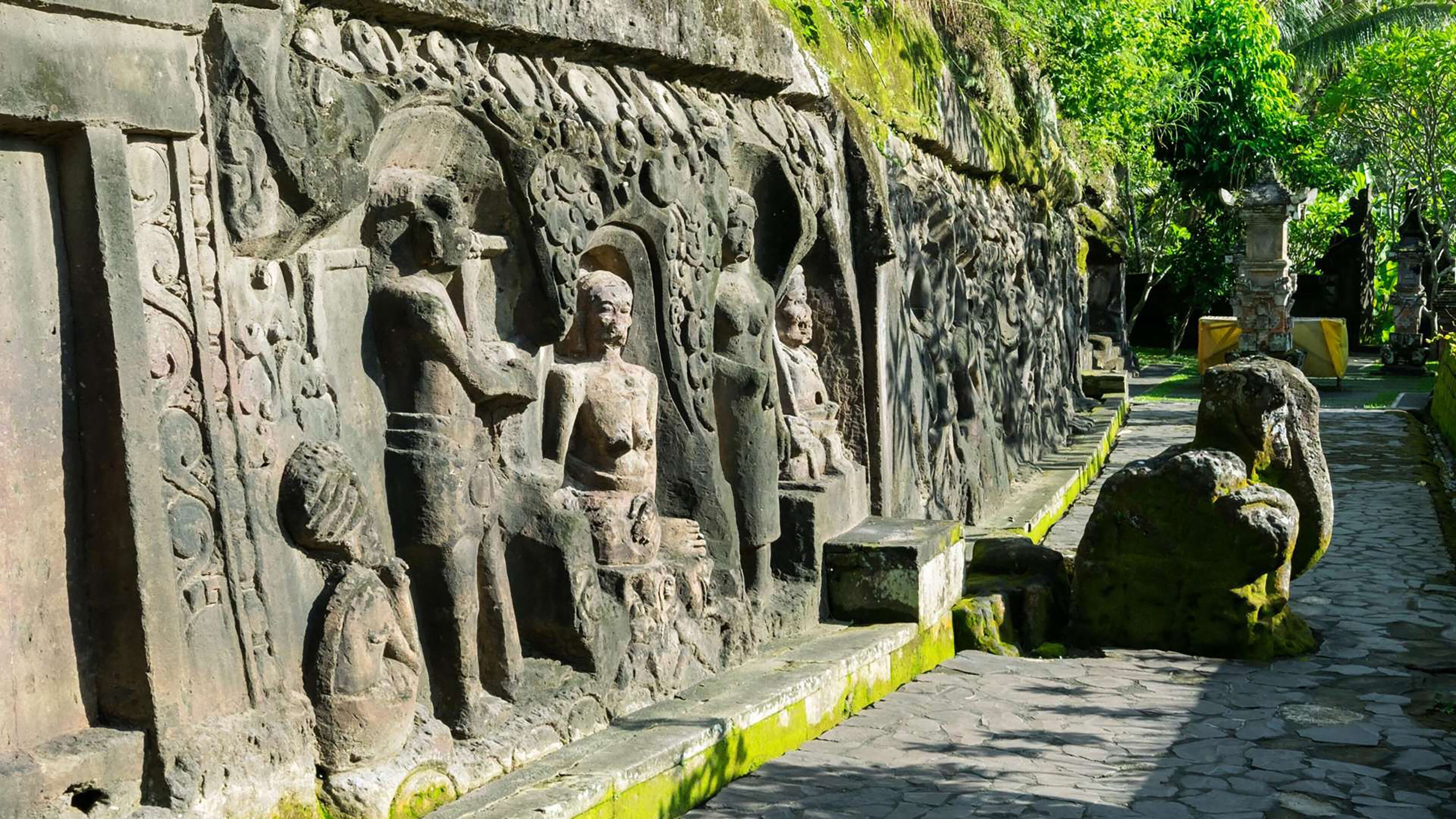 A stone pathway with carved figures and a stone bench.