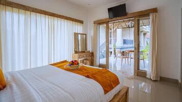 A hotel room with a bed, a wooden dresser, a television, and a balcony with a table and chairs.