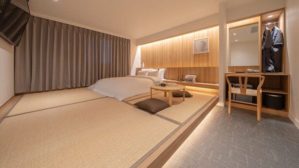 A hotel room with a bed, bedside table, and a desk with a chair. - Cheoan Monolith Hotel (Cheonan)