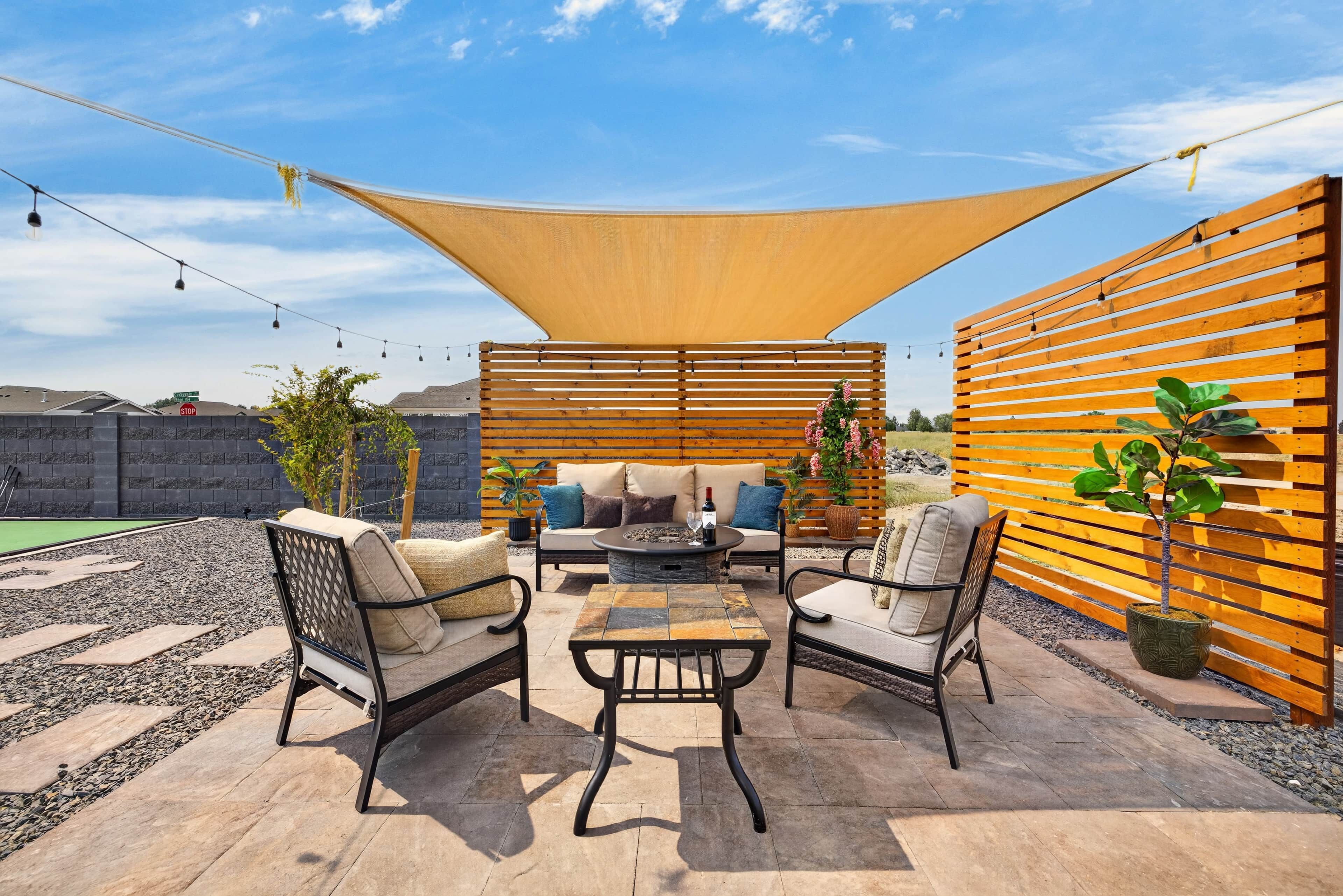 Un patio al aire libre con zona de estar, una mesa y un hogar para fuego.