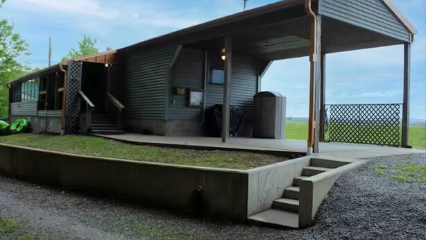 A modern building with a covered porch, a small outdoor seating area, and a view of the landscape. - Copper Roof Getaway Golconda, Il (Golconda)