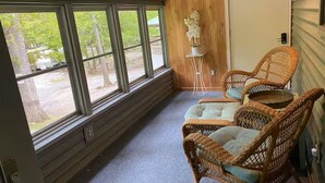 A room with large windows, wicker chairs, a small table, and a white door. - Copper Roof Getaway Golconda, Il (Golconda)