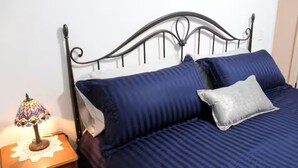 A bed with a metal frame, a blue bedspread, and a white pillow. - Copper Roof Getaway Golconda, Il (Golconda)