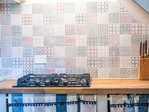 A kitchen with a gas stove, a wooden countertop, and a patterned backsplash. - Fibbialla by Interhome (Pescia)