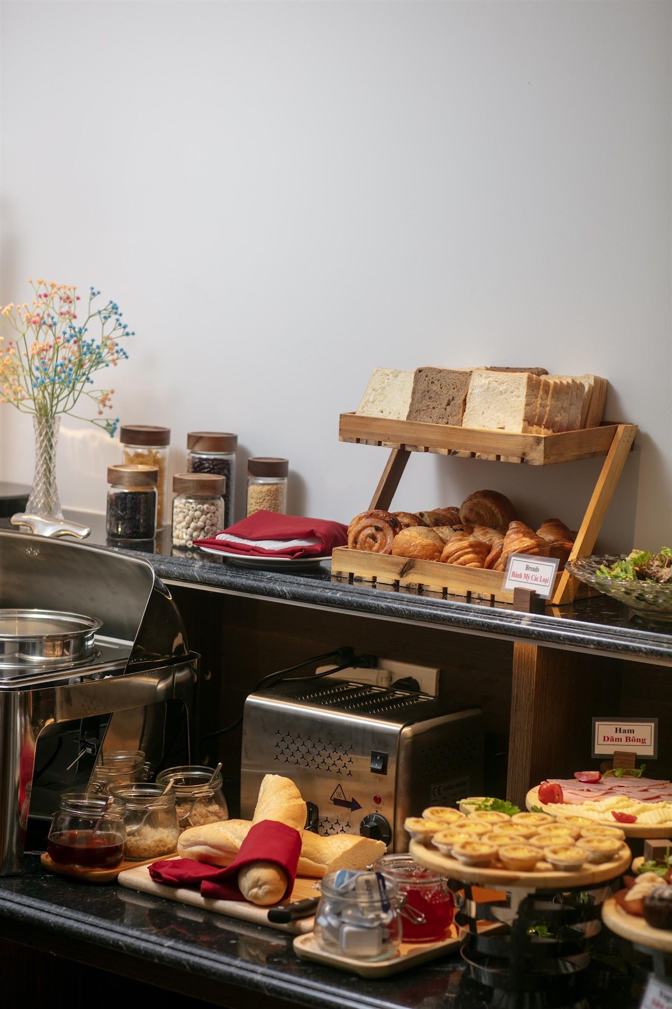 A buffet with various food items, including bread, pastries, and condiments.