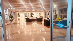 Eine großzügige Lobby mit poliertem Boden, einem Empfangsbereich, einer Sitzecke und Zimmerpflanzen.