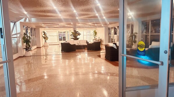 A spacious lobby with a polished floor, a reception desk, seating area, and potted plants. - Vrbo Property (Carolina)