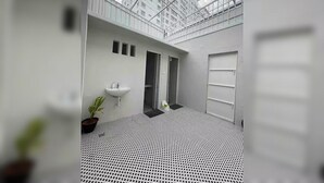 Ein modernes Badezimmer mit einem geometrisch gemusterten Boden, einem Waschbecken und einer Topfpflanze.