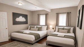 A bedroom with two beds, a large rug, a wall-mounted light fixture, and a cloud-themed painting. - McCormick Meetup - Prime Location - Sleeps 16 (Chicago)