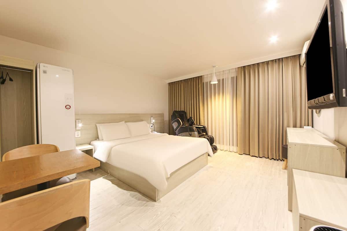 Une chambre d’hôtel équipée d’un lit, d’un bureau, d’une chaise, d’une télévision et d’une armoire.