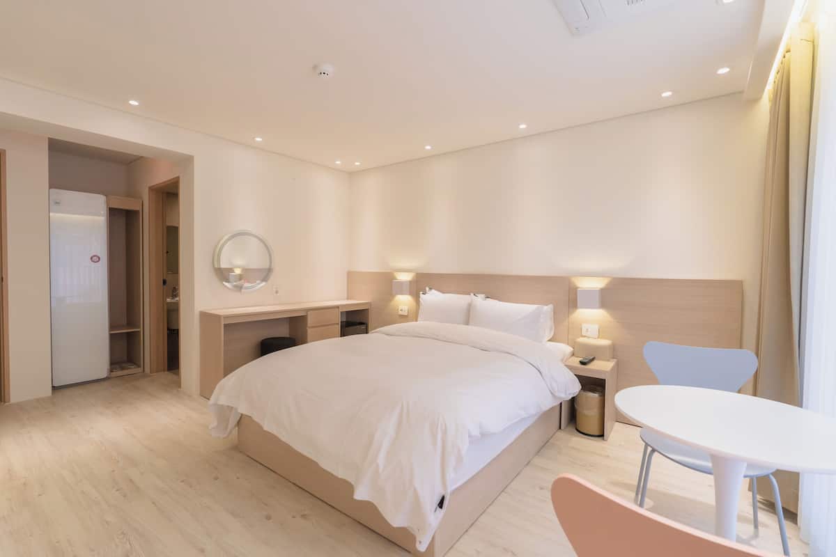 Une chambre d’hôtel moderne équipée d’un lit, d’une table de chevet, d’une lampe, d’une chaise et d’une petite table.