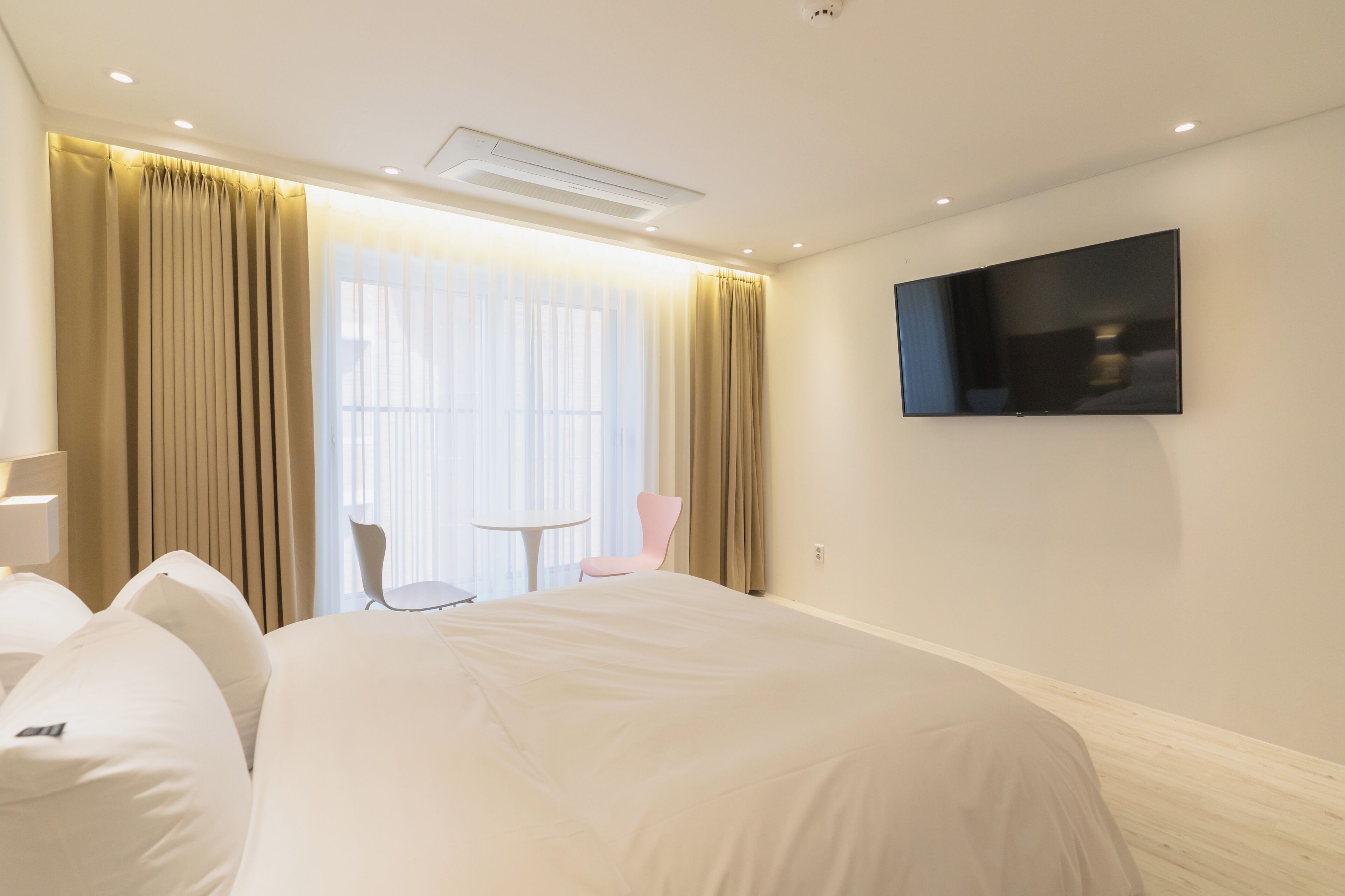 A hotel room with a bed, a TV, a chair, and a small table.