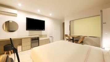 A modern hotel room with a bed, a TV, a desk, and a large window.