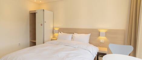 A hotel room with a bed, a wardrobe, a bedside table, and a chair.