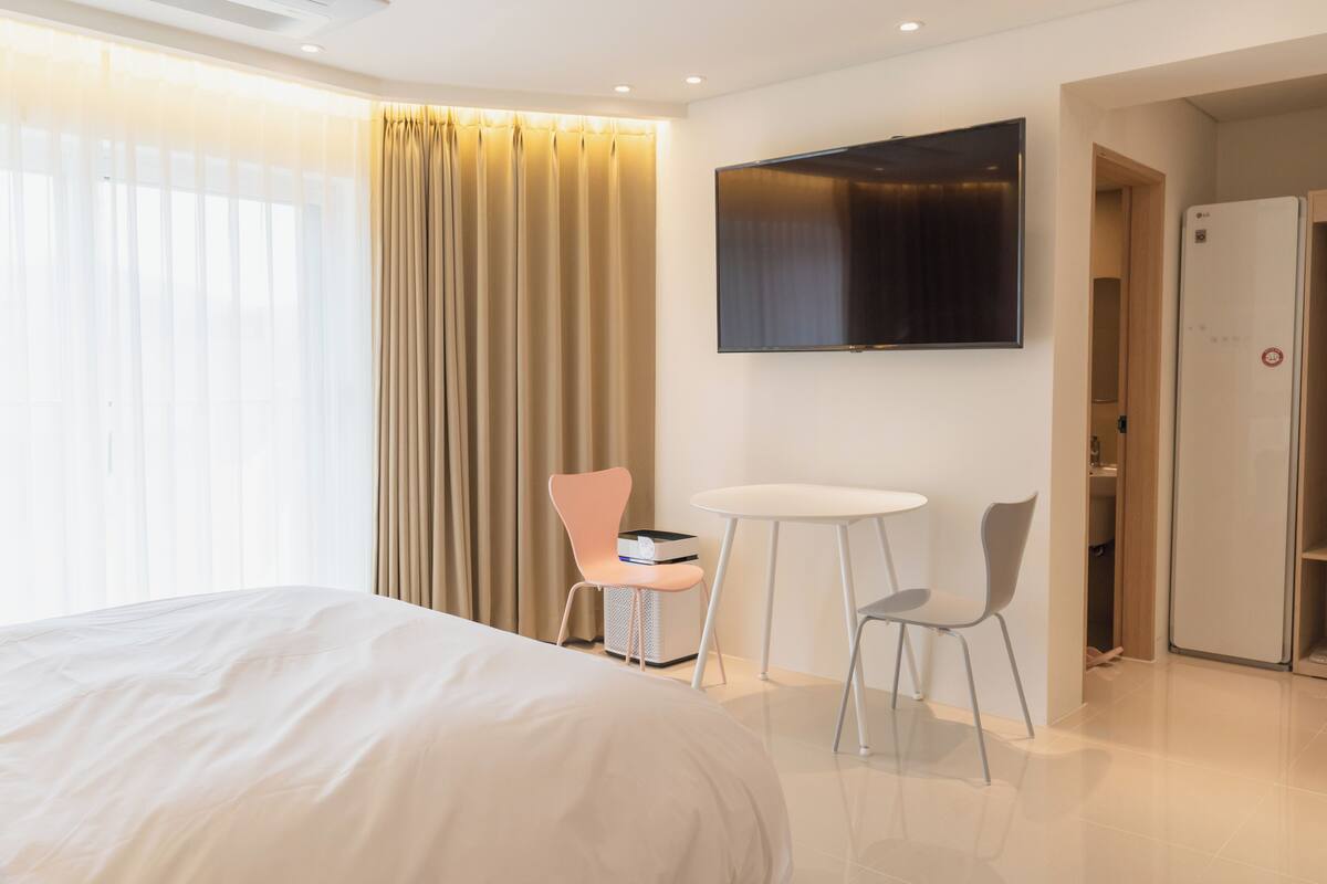 Une chambre d’hôtel comprenant un lit, un téléviseur fixé au mur, une petite table, deux chaises et un mini-bar.