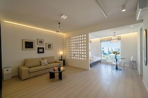 A modern living room with a sofa, coffee table, and a dining area with a table and chairs.