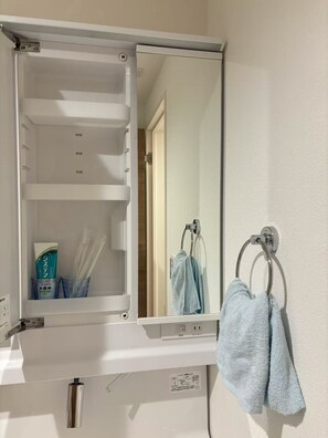 Ein Badezimmer mit Spiegel, Handtuchhalter und Ablage für Pflegeprodukte.