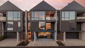 A modern multi-story residential building with large windows, a central staircase, and a visible living area. - The Beech Penthouse - Stunning Lake and Mountain Views (Queenstown)