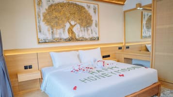 A hotel room with a large bed, a headboard, a bedside table, a nightstand, a mirror, and a wall-mounted artwork.
