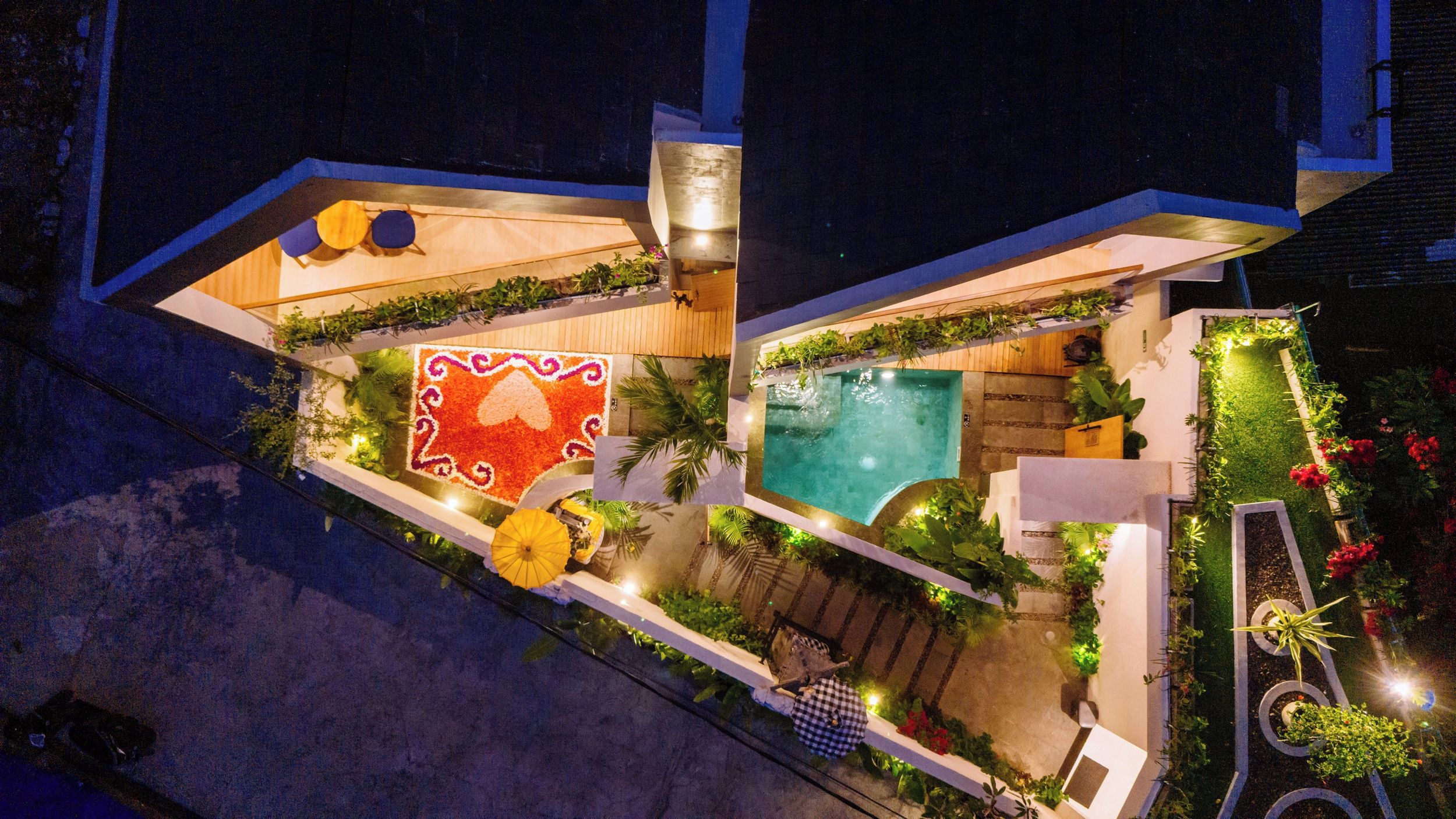 A rooftop with a swimming pool, a red patterned area, and a small garden.
