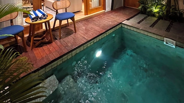 Una casa moderna con piscina, comedor y una escalera que lleva a un nivel superior.
