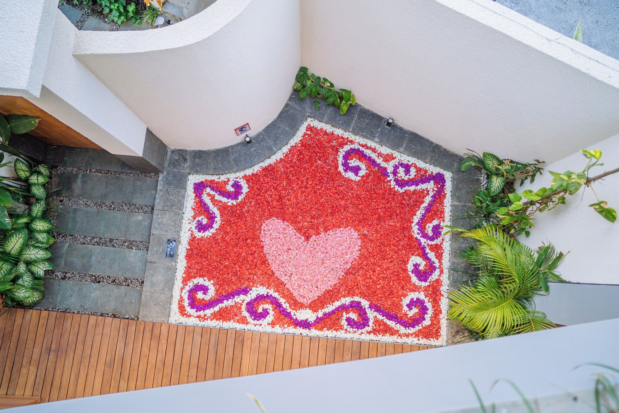 A red and white patterned mat with a heart design, placed on a wooden deck.