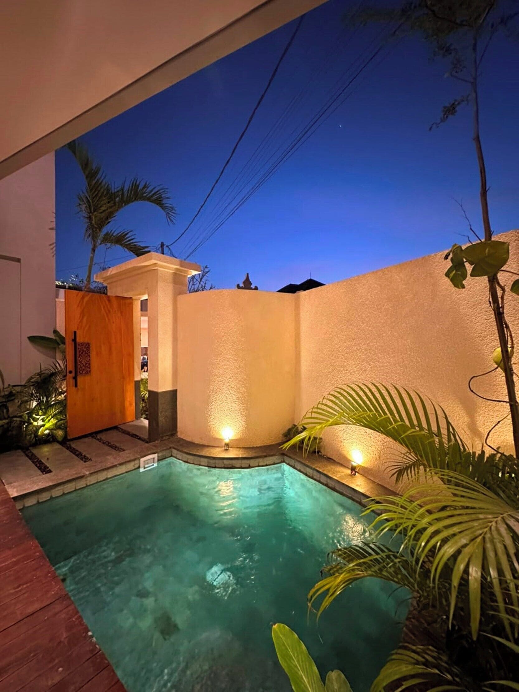 A swimming pool with a wooden door and a light fixture on the wall.