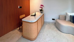 Un interior moderno con una mesa de recepción, un ventilador de techo y un sofá.