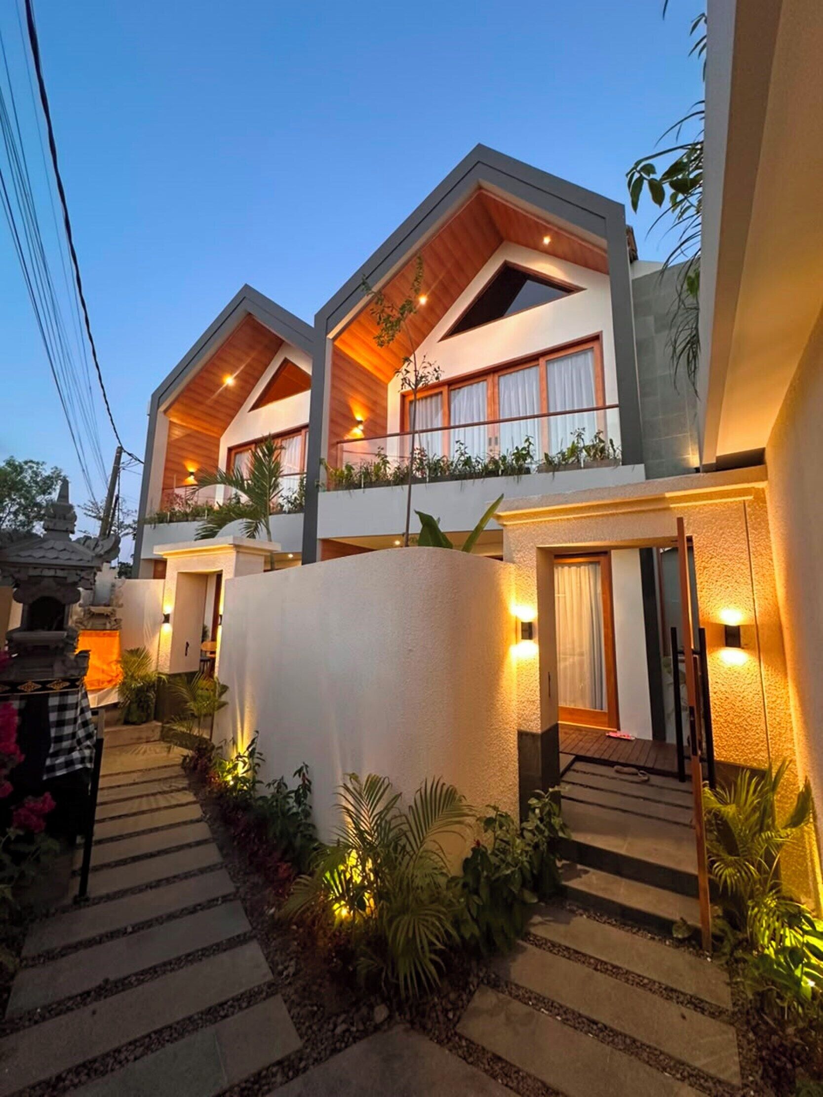 A modern two-story house with a covered patio and a garden pathway.