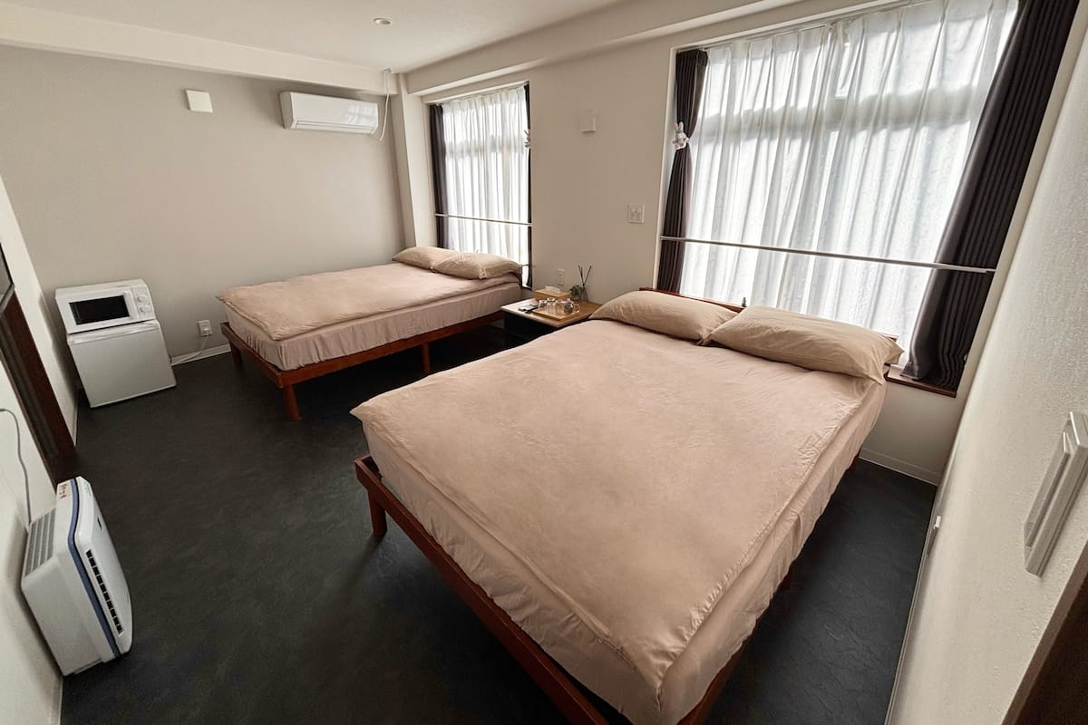 Een hotelkamer met twee enkele bedden, een klein tafeltje, een magnetron en een airconditioning.