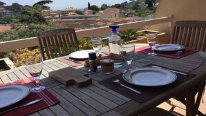 A wooden table set for dining with a view of a hillside town. - Vacation rental 2 bedrooms, air conditioning, Wi-Fi, balcony, barbecue, private parking (ST MANDRIER SUR MER)