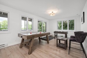 A spacious room with a foosball table, a pool table, and a comfortable seating area with a chair.