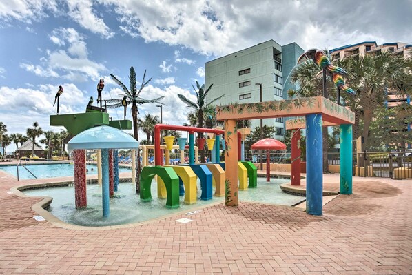 Una zona de juegos acuáticos con estructuras coloridas y una piscina.