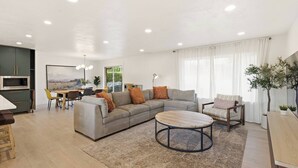 Ein modernes Wohnzimmer mit Sofa, Couchtisch und Essbereich.