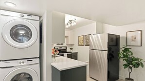 Eine moderne Küche mit einem Edelstahl-Kühlschrank, einer Waschmaschine und einer zentralen Kochinsel mit einer Blumenvase.