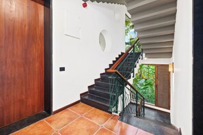 A staircase with a wooden handrail, black steps, and a green metal railing.