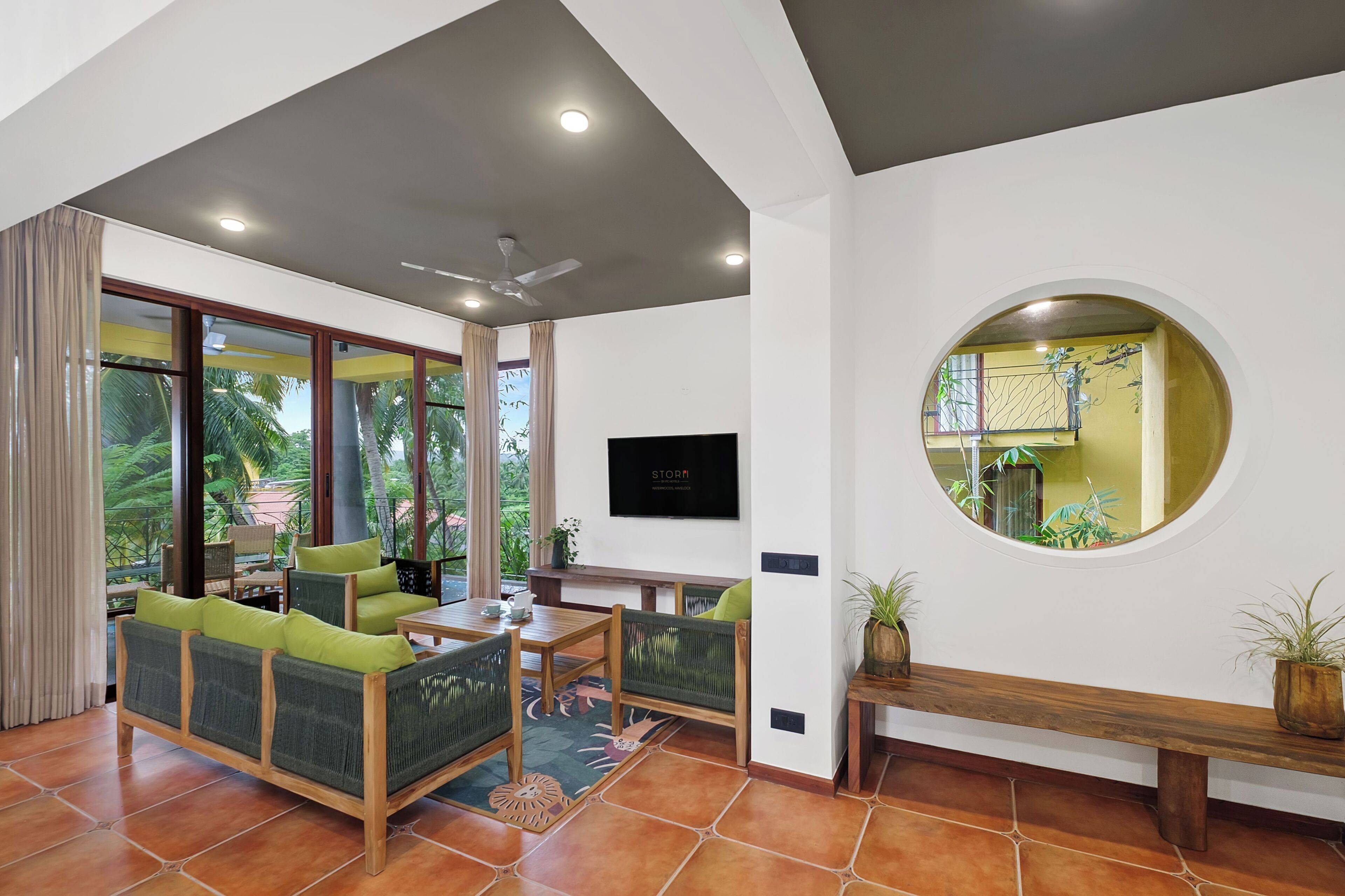 A modern room with a dining area, a ceiling fan, a television, and a large window with curtains.